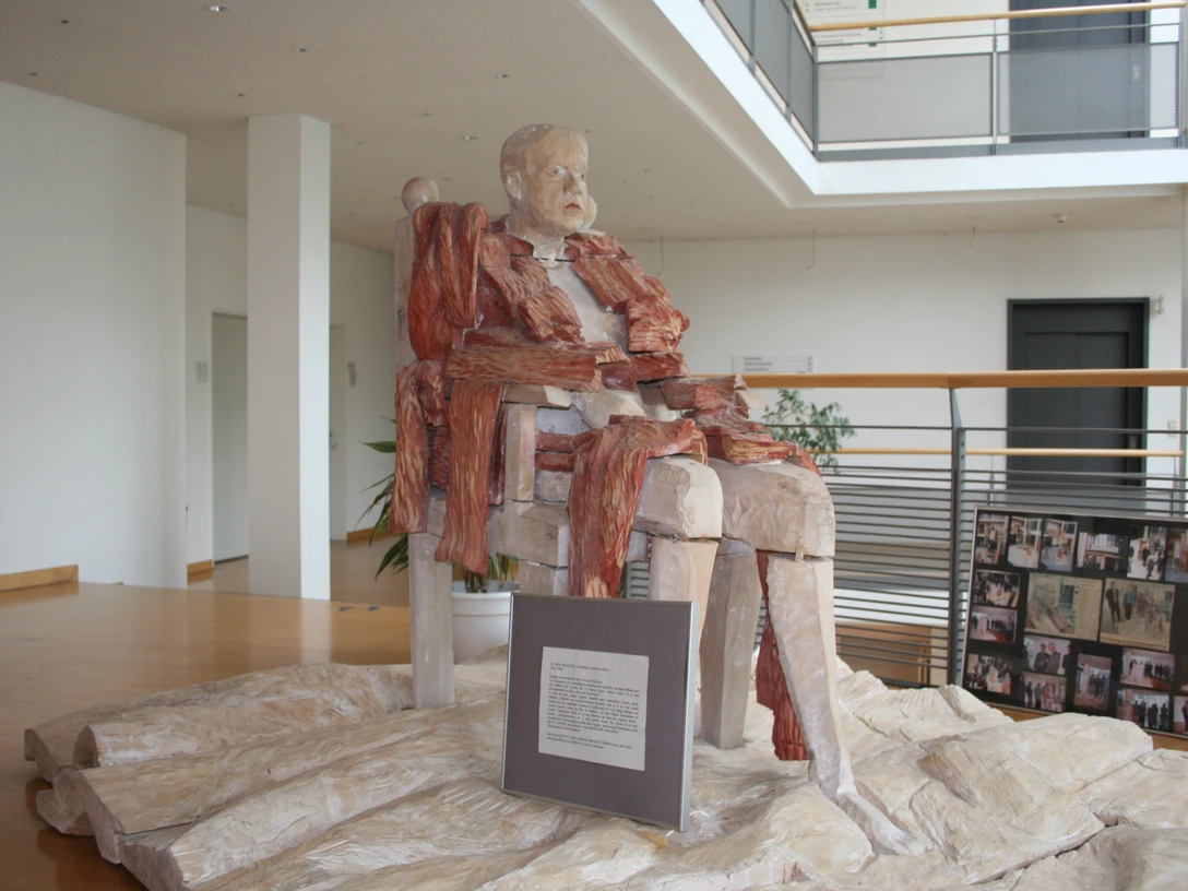 Skulptur Der Patriarch Fijodor Karamasow Eine beeindruckende Skulptur von Fijodor Karamasow, der in einem modernen Innenraum posiert.