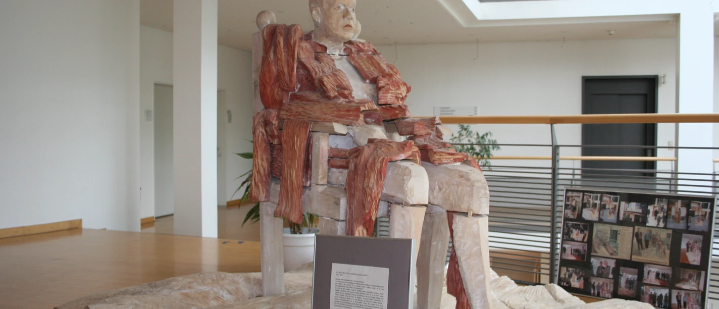 Skulptur Der Patriarch Fijodor Karamasow Eine beeindruckende Skulptur von Fijodor Karamasow, der in einem modernen Innenraum posiert.