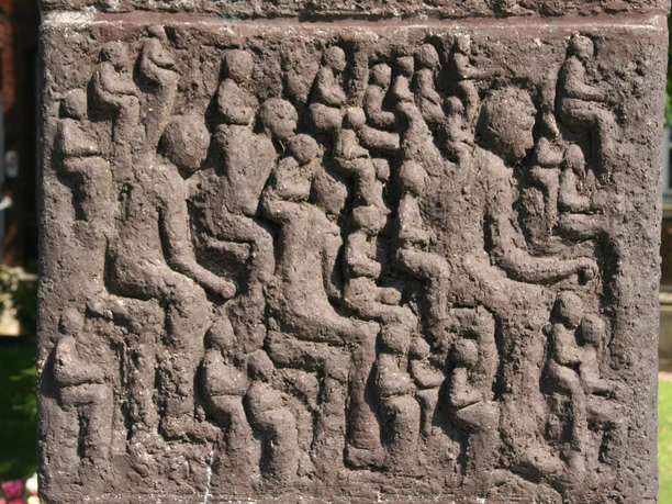 Relief einer Steinplatte mit zahlreichen stilisierten Menschenfiguren, in Leseposen vertieft.
