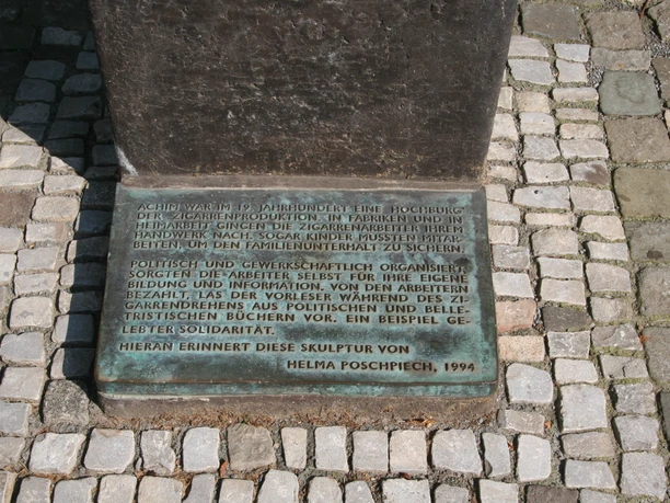 Bronzestatue eines sitzenden Mannes mit Buch, erinnert an politische Bildung in Achim.