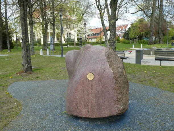 Skulptur "Freund von Weser" Großer, polierter Granitblock mit glatter Oberfläche, im Park auf blauem Kiesbett platziert.