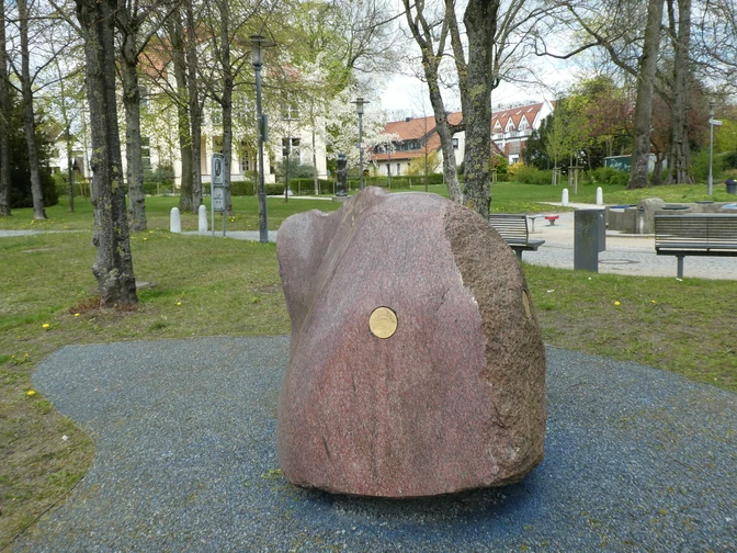 Skulptur "Freund von Weser" Großer, polierter Granitblock mit glatter Oberfläche, im Park auf blauem Kiesbett platziert.