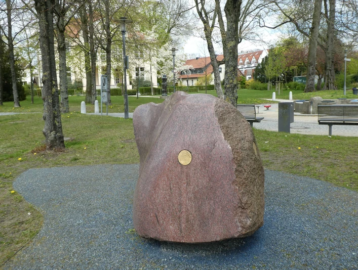 Skulptur "Freund von Weser" Großer, polierter Granitblock mit glatter Oberfläche, im Park auf blauem Kiesbett platziert.