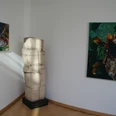 Skulptur in einem Raum neben Leinwandbildern, dargestellt in minimalistischem Stil mit natürlichen Motiven.