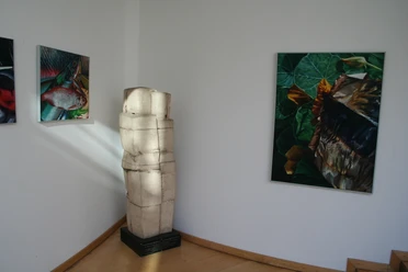 Skulptur "Knirschende Beziehung" Skulptur in einem Raum neben Leinwandbildern, dargestellt in minimalistischem Stil mit natürlichen Motiven.