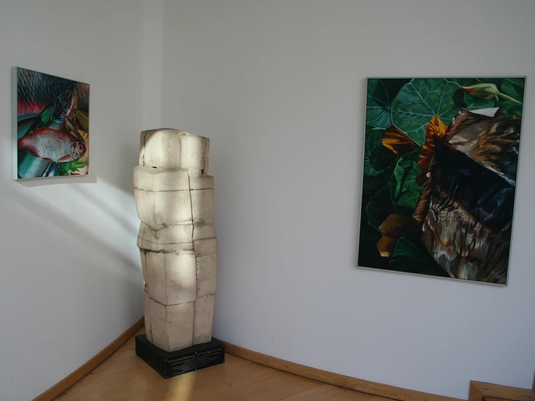 Skulptur "Knirschende Beziehung" Skulptur in einem Raum neben Leinwandbildern, dargestellt in minimalistischem Stil mit natürlichen Motiven.