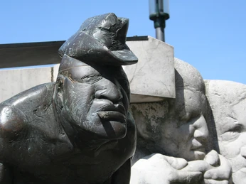 Bronzeskulptur eines Zigarrenmachers mit markantem Gesichtsausdruck und drei umstehenden Figuren.