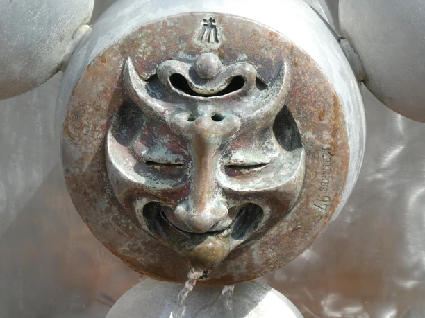 Brunnenfigur in Achim mit interessanter Maske. Wasser fließt aus einem skulpturalen Gesicht.