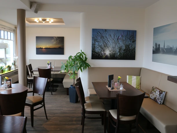 Gemütliche Einkehr Das Bild zeigt die gemütliche Einrichtung des Cafés, die in warmen Braun- und Naturtönen gehalten ist und eine einladende Atmosphäre schafft.