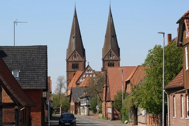 Zwei beeindruckende Kirchtürme ragen in den Himmel über der schläfrigen Straße in Bücken.