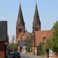 Zwei beeindruckende Kirchtürme ragen in den Himmel über der schläfrigen Straße in Bücken.