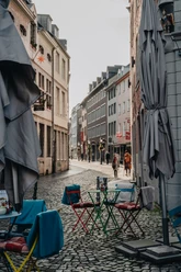 Bunte Caféstühle und Tische auf Kopfsteinpflaster mit Blick in die Blick in die Straße.