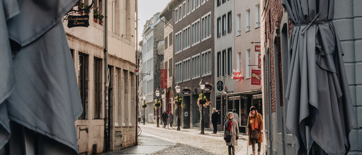 Annastraße.jpg Bunte Caféstühle und Tische auf Kopfsteinpflaster mit Blick in die Blick in die Straße.