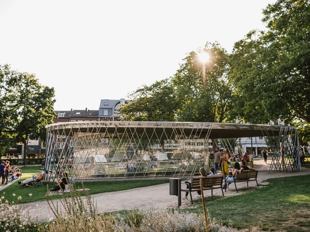 Eine modern gestaltete Glasvitrine im Park, wo Besucher*innen die archäologischen Ausstellungsstücke bewundern können.