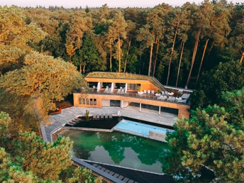 Das WALDgarten Westfalen Therme zeigt ein modernes Gebäude mit Pool, umgeben von dichtem Wald.