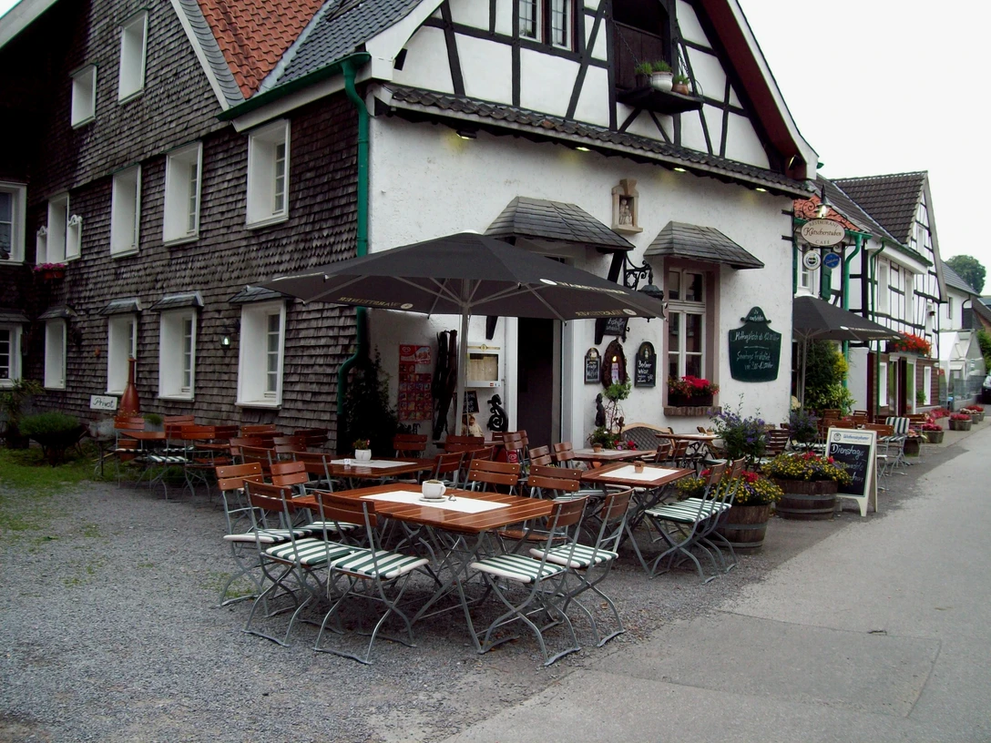 Kutscherstuben Traditionelles Fachwerkhaus mit Biergarten, Holztische und Stühle, einladende ländliche Atmosphäre.