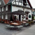 Kutscherstuben Traditionelles Fachwerkhaus mit Biergarten, Holztische und Stühle, einladende ländliche Atmosphäre.