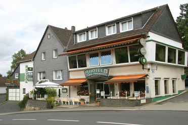 Hotel Laber Ein traditionelles Hotel mit Café, großer Fensterfront und Außenterrasse an einer kurvigen Straße.