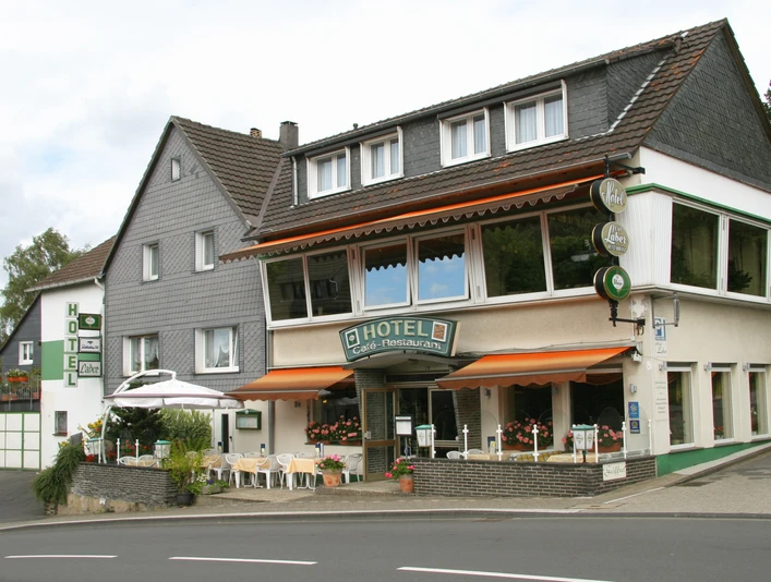 Hotel Laber Ein traditionelles Hotel mit Café, großer Fensterfront und Außenterrasse an einer kurvigen Straße.