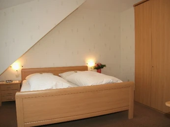 Hotel Laber Ein schlichtes Schlafzimmer mit Doppelbett, zwei Nachttischen und einem großen Holzkleiderschrank.
