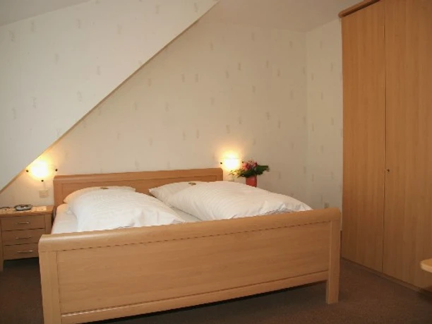 Hotel Laber Ein schlichtes Schlafzimmer mit Doppelbett, zwei Nachttischen und einem großen Holzkleiderschrank.