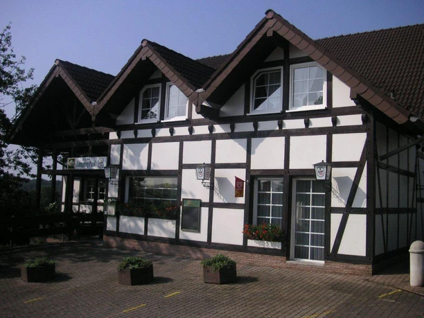 Vorderansicht Restaurant "Zum Camping Paul" Fachwerkhaus mit drei Giebelfenstern, Blumenkästen an den Fenstern, sonniger Tag, blauer Himmel.