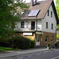 Restaurant "Zum Parkhaus" Gasthaus "Zum Parkhaus" mit Ziegeldach, weißen Wänden, umgeben von Bäumen und einer Straße davor.