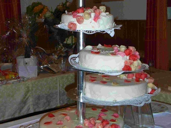 Restaurant "Zum Parkhaus" Eine vierstöckige Hochzeitstorte mit weißem Zuckerguss und rosa Blütenarrangements.