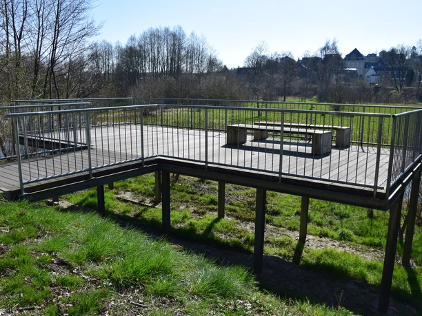 Wupperbalkon an den Ohler Wiesen Holzplattform mit Geländer bietet Sitzgelegenheit, umgeben von Natur und Wiesen, im Sonnenschein.