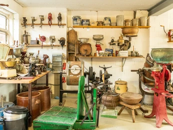 Technik- und Bauernmuseum Eine Sammlung historischer landwirtschaftlicher Geräte in einem Ausstellungsraum mit Regalen.