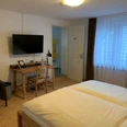 Das Märchenwald Hotel Helles Hotelzimmer mit Doppelbett, Schreibtisch, Fernseher, Sessel und angrenzendem Bad zu sehen.