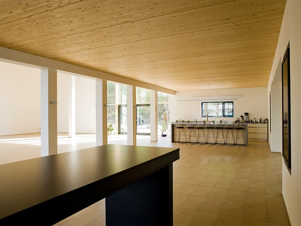 Foyer Heller Raum mit Holzbalkendecke, großem Panoramafenster, Barhockern und freistehendem Tresen.