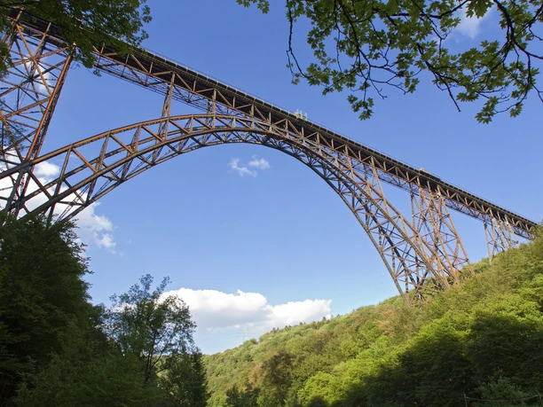 Müngstener Brücke Hoch über bewaldetem Tal überspannt die Müngstener Brücke zwischen Bäumen den blauen Himmel.