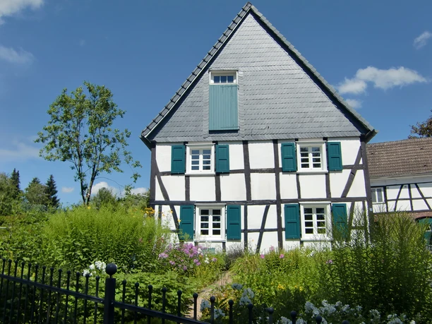 Fachwerk in Reichshof-Heischeid Fachwerkhaus in Reichshof, umgeben von blühendem Garten und markanten blauen Fensterläden.