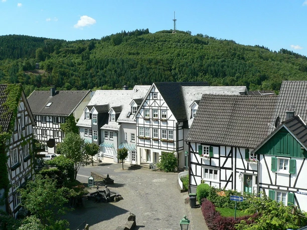 Fachwerkhäuser in Morsbach Fachwerkhäuser in einem idyllischen Dorf vor bewaldeten Hügeln unter klarem, blauem Himmel.