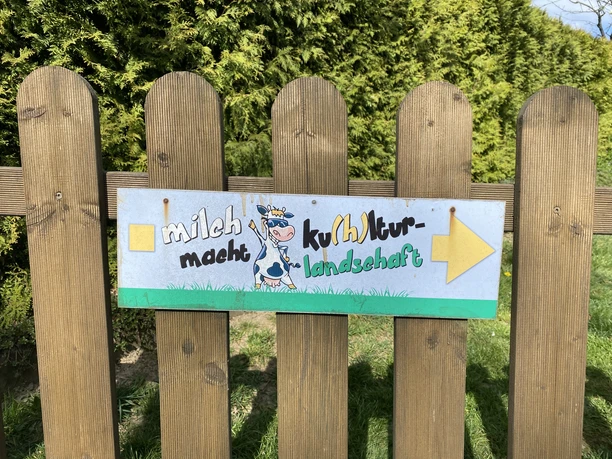 Wegweiser Milchweg <p>Schild mit der Aufschrift "Milch macht ku(h)ltur - Landschaft" an einem Holzzaun. </p>