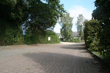 Wanderparkplatz "Oldendorfer Schweiz" Gepflasterter Parkplatz umgeben von Bäumen und Sträuchern, blauer Himmel im Hintergrund.