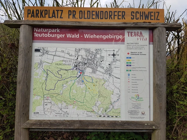 Informationstafel beschreibt Wanderwege im Naturpark Teutoburger Wald-Wiehengebirge, nahe Parkplatz.
