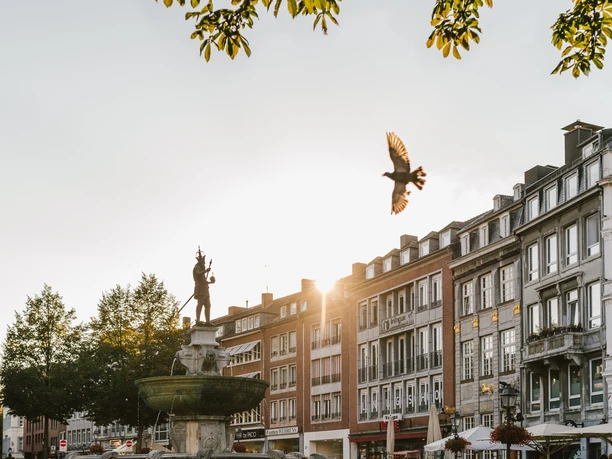 Marktplatz Aachen mit Karlsbrunnen Der Aachener Marktplatz mit dem Karlsbrunnen im Vordergrund, dahinter historische Gebäude im Sonnenuntergang.