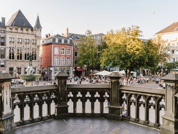 Marktplatz Aachen von Rathaustreppen Belebter Marktplatz, aufgenommen von den Rathaustreppen aus, mit historischen Gebäuden und dem Karlsbrunnen in der Mitte.