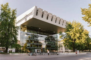 Super C Aachen Modernes Gebäude in C-Form mit Glasfront und einem Vorplatz, umgeben von grünen Bäumen.