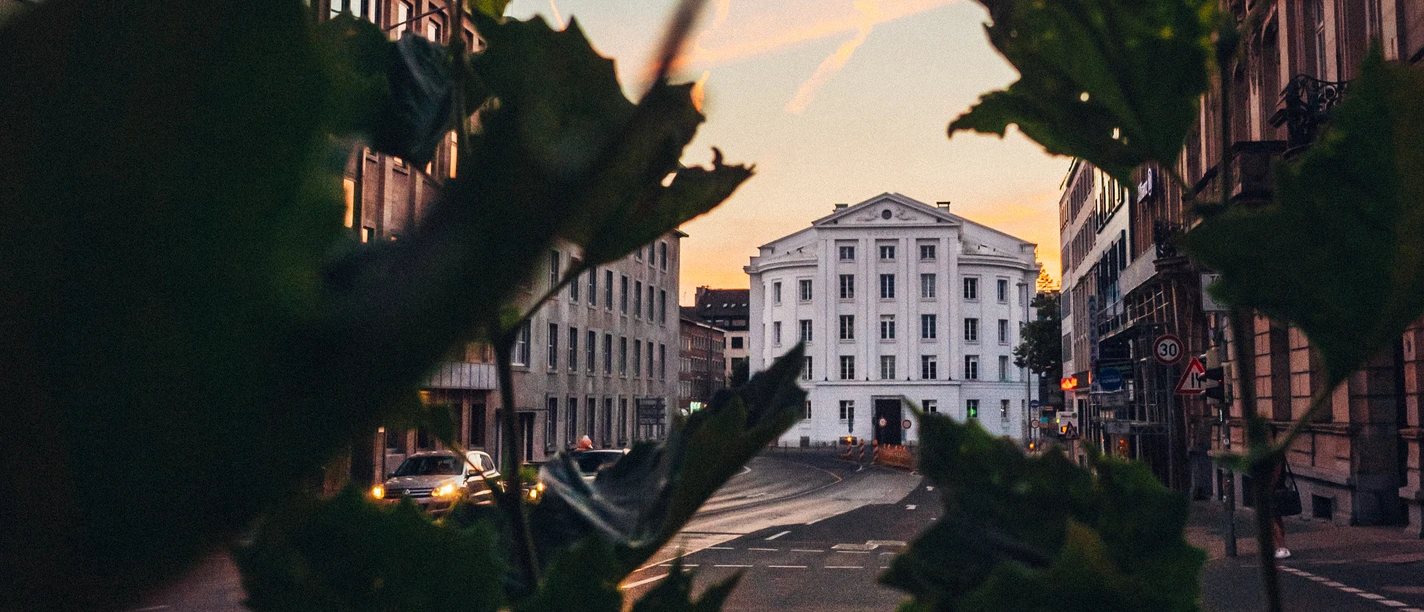 Blick auf das Theater Aachen durch Zweige und Blätter hindurch.