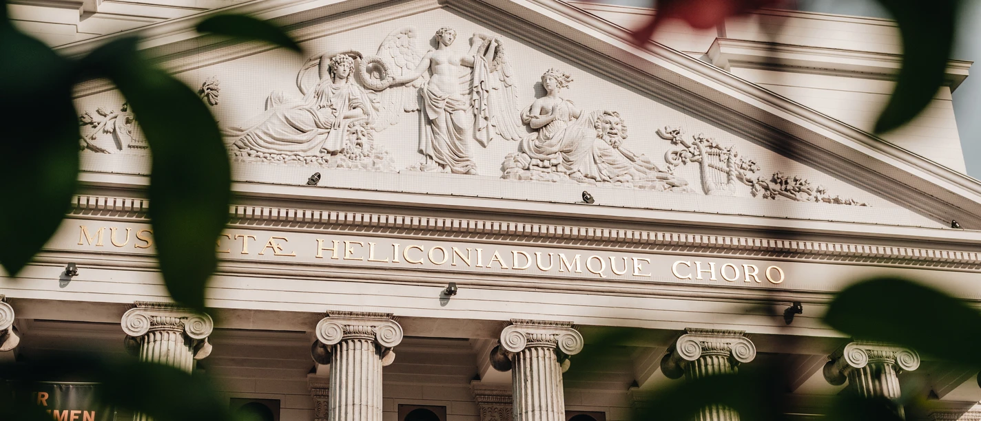 Blick auf die Vorderseite des Theaters Aachen durch Blätter hindurch.