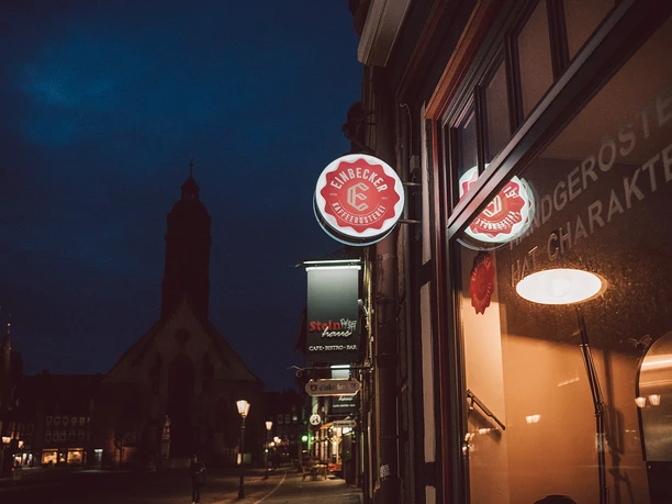 Exterior view of the Einbeck coffee roastery in the evening, with the large market church in the background.