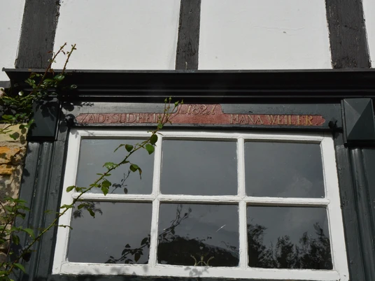 Eingangsbereich Speicherhaus Fachwerkfassade mit Inschrift "A.D. 1682", die über einer mit kleinen Fensterscheiben verzierten Tür prangt.