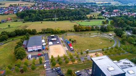 Generationenpark Luftaufnahme eines Parks mit Wiesen, Spielplätzen und Wegen, umgeben von dörflicher Landschaft.