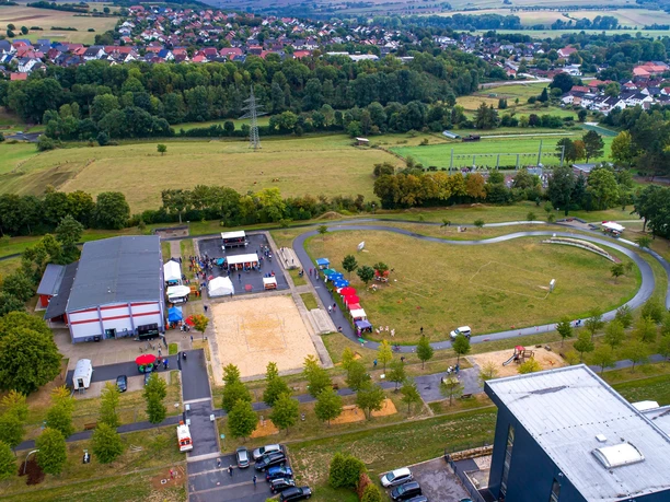 Generationenpark Luftaufnahme eines Parks mit Wiesen, Spielplätzen und Wegen, umgeben von dörflicher Landschaft.