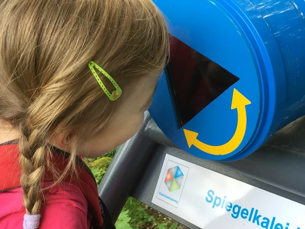 Ein Kind schaut in ein blaues Spiegelscope, das ein kaleidoskopisches Erlebnis bietet.