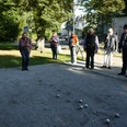 Boule-Bahn am Kurpark Das Bild zeigt mehrere Menschen, die an der Boulebahn stehen und gerade spielen. Das Wetter ist sonnig, und der Kurpark erblüht in voller Pracht.