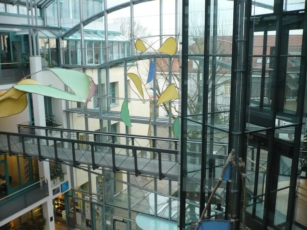 Kinetische Skulpturen mit bunten Elementen schweben im lichtdurchfluteten Foyer des Rathauses.